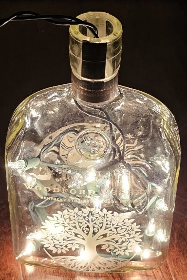 whisky bottle that has been laser engraved with a sun and moon image and has LED lights inside