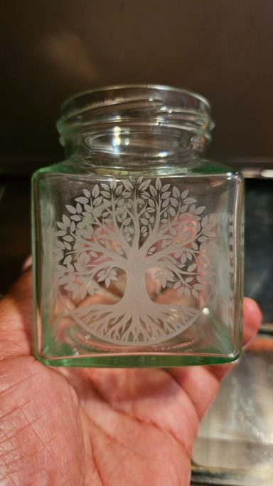 jar with tree of life on one side, sun and moon graphic on the other