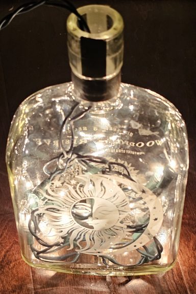 whisky bottle that has been laser engraved with a sun and moon image and has LED lights inside